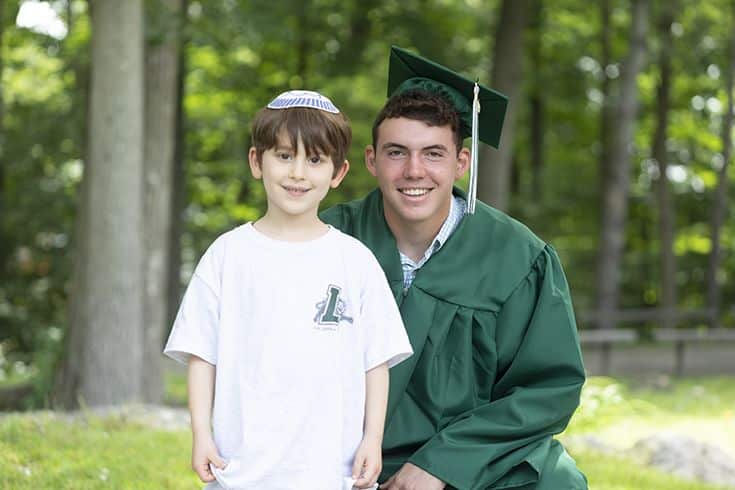 A graduating student posing for a photo with a young student