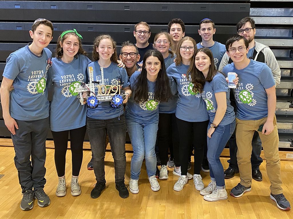 A group of students in matching t-shirts posing for a photo smiling