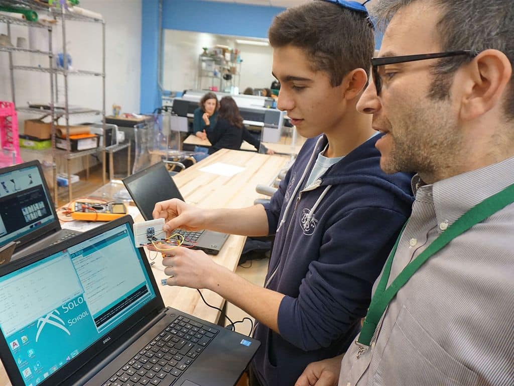 A student and a teacher collaborate on a computer in a laboratory setting, focused on their work.
