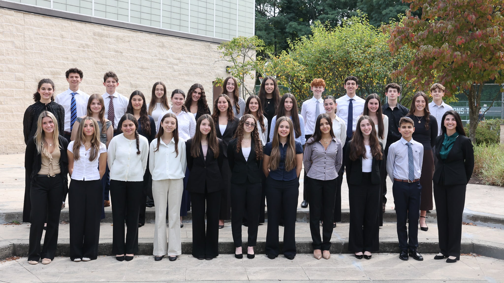 Group photo of Independent Science Research students in business attire in a sunny outdoor space.
