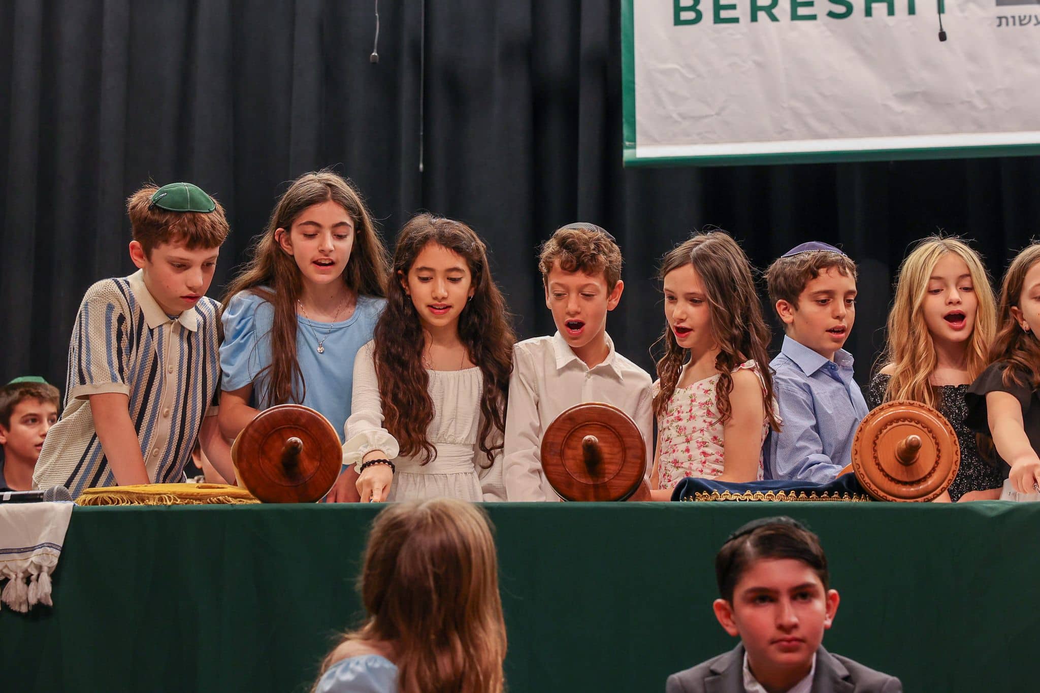 Group of children reading Torah together onstage in the Lower School auditorium